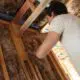 A young man puts insulation batting in between a wall's wood frame in a new construction home