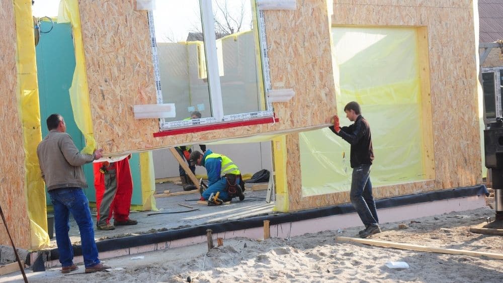 Builders installing a modular home panel.