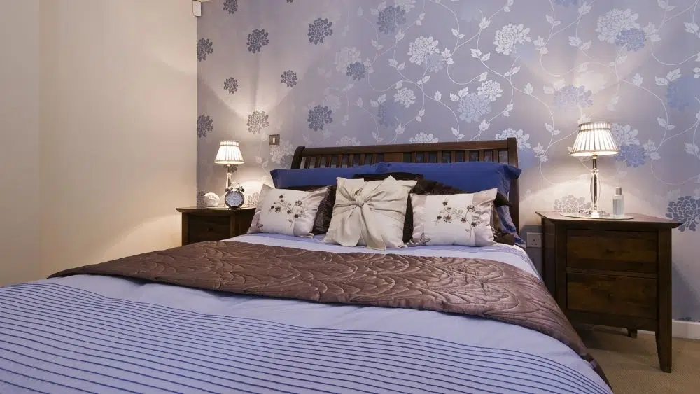 Bedroom with floral accent wall and lamps on the bedside tables.