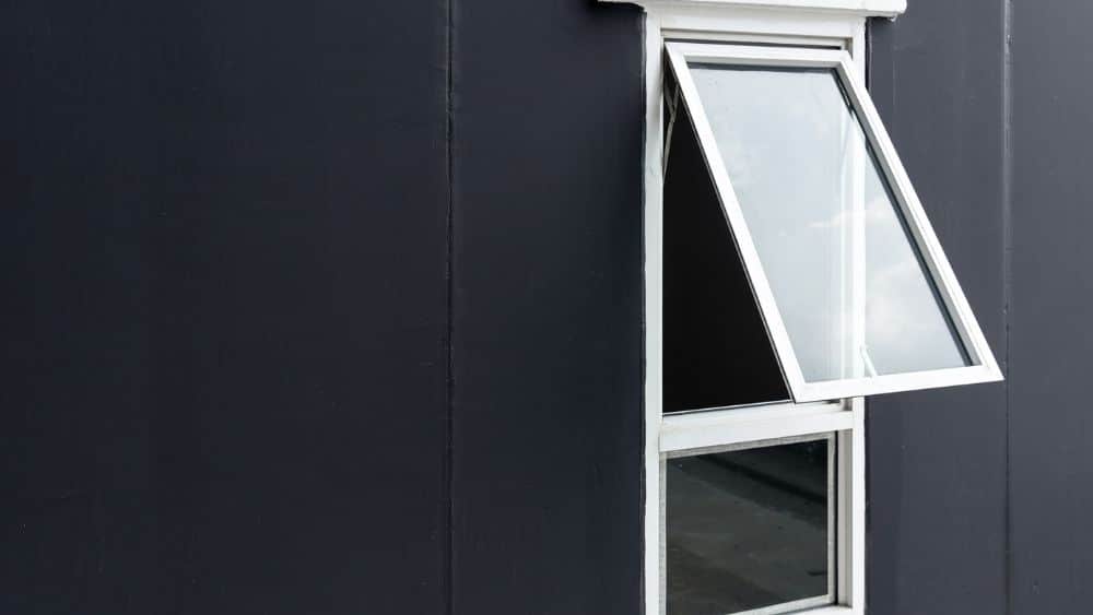 An opened in awning window set into a black wall.