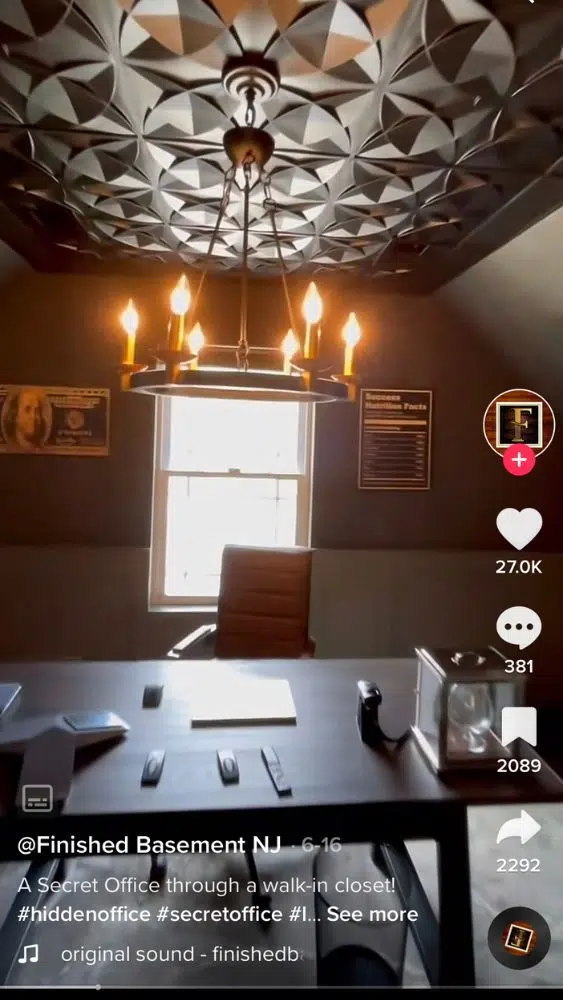 Screenshot of @finishedbasementnj's TikTok video showing the dark textured ceiling with a modern chandelier hanging from the center.