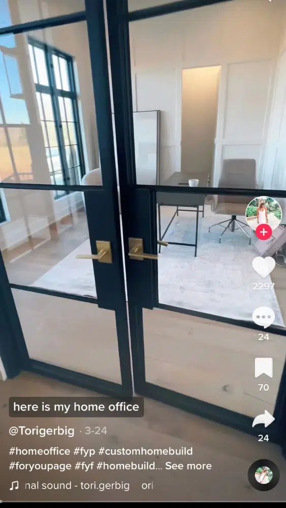 Screenshot of @torigerbig's TikTok video showing glass French doors with blue trim and gold level handles that open into an office.