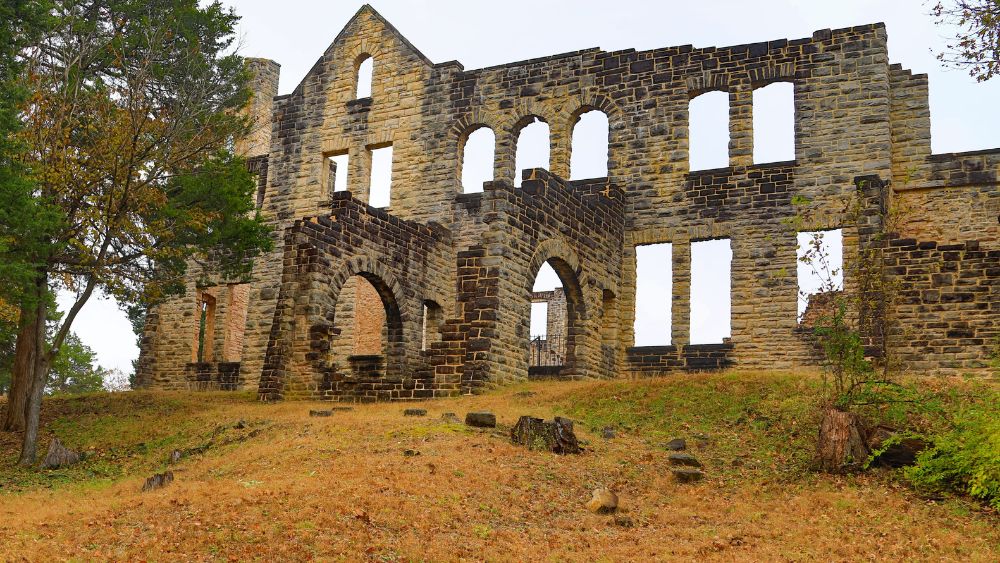 Ruins of the front of a building that looks like a castle with many arched windows.