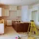 kitchen renovation showing white cabinets on walls and brown island cabinets with tools and yellow stepladder