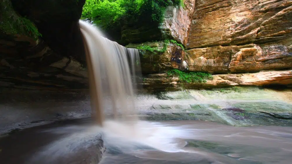 A waterfall cutting through an opening in a rockface.