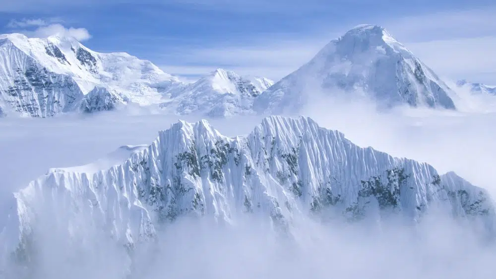 Mountains covered in snow above the clouds.