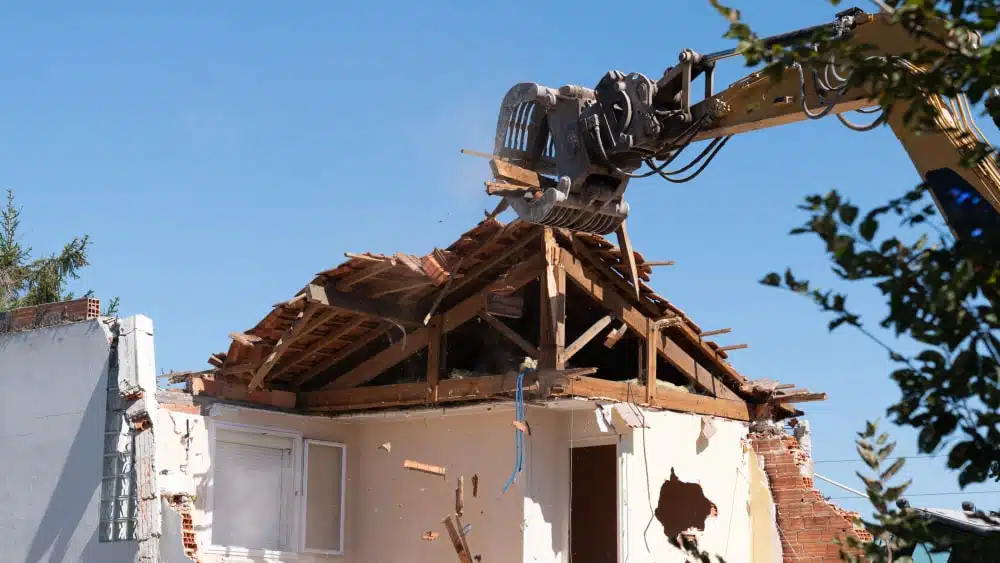 bulldozer pulls down roof of home being demolished
