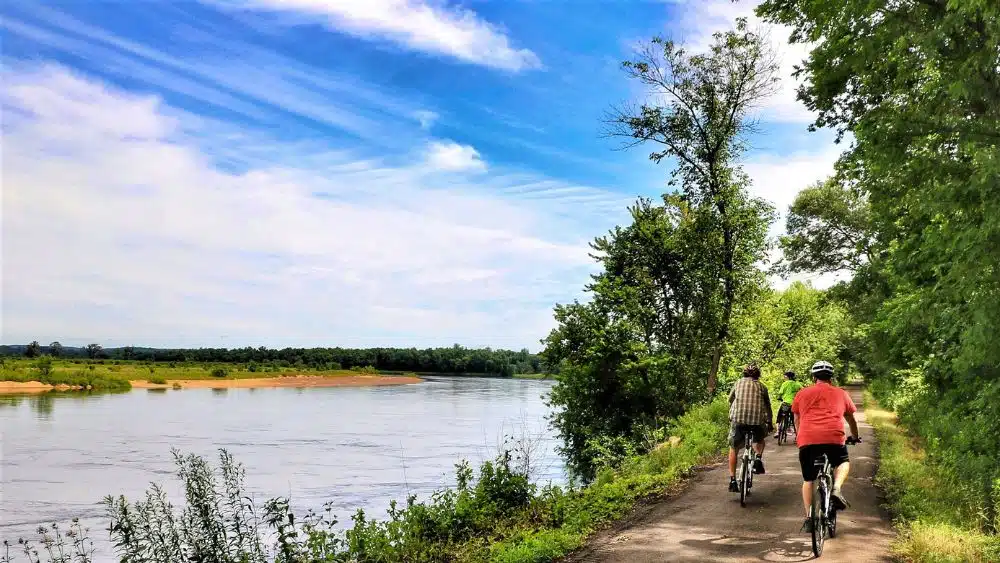 People biking on a trail next to a body of water.