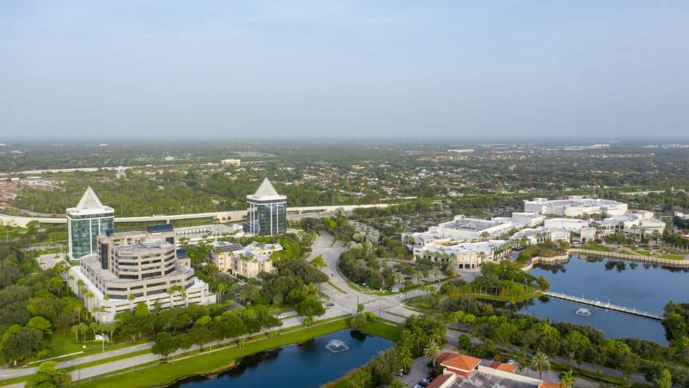 Aerial of a large hotel and expansive mall in a suburb area.