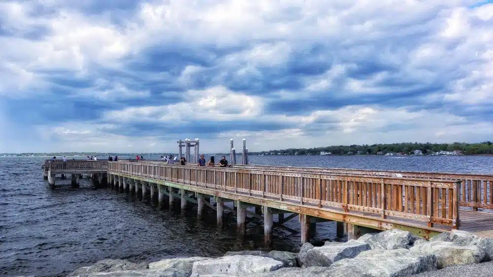 People walking on wooden pier on Narragansett Bay at Colt State Park, Rhode Island