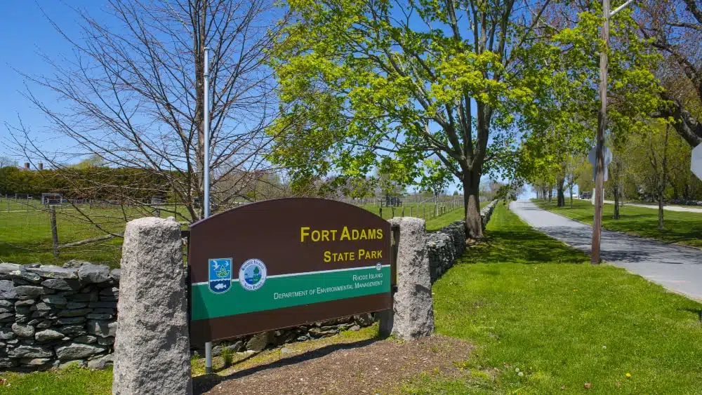 View of entrance sign to Fort Adams State Park. Sign reads Fort Adams State Park, Rhode Island, Department of Environmental Management