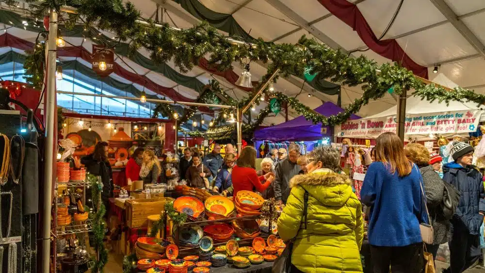 A holiday market with people walking around looking at artisan goods.