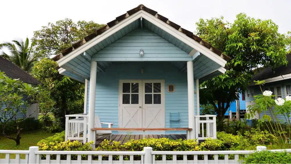 quaint tiny home with blue siding and white fence