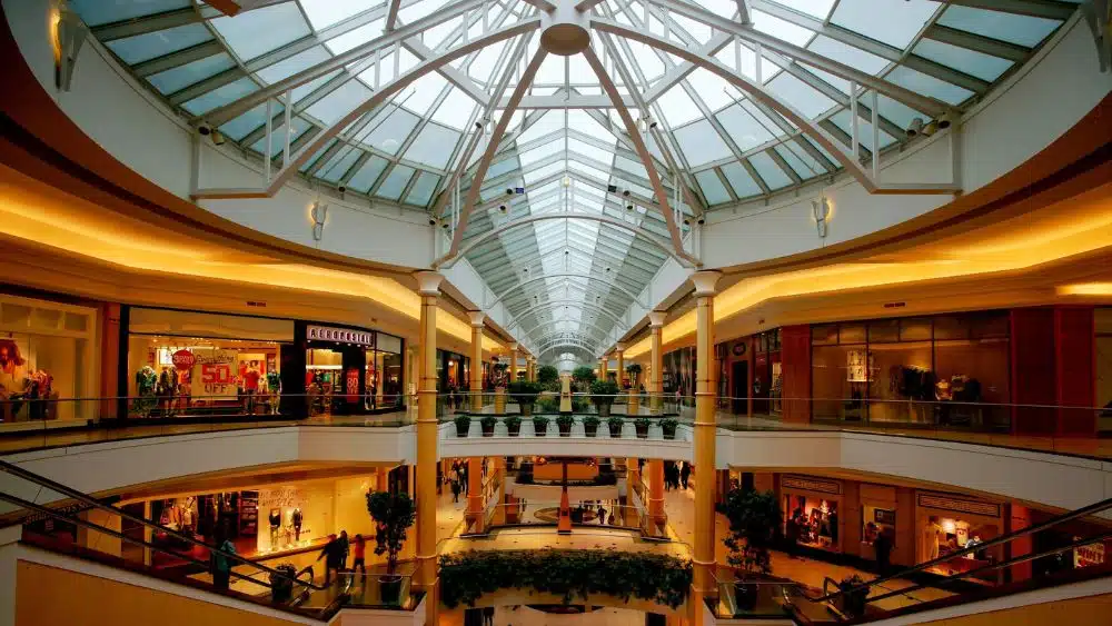 Interior of a shopping mall with a glass ceiling and two floors.
