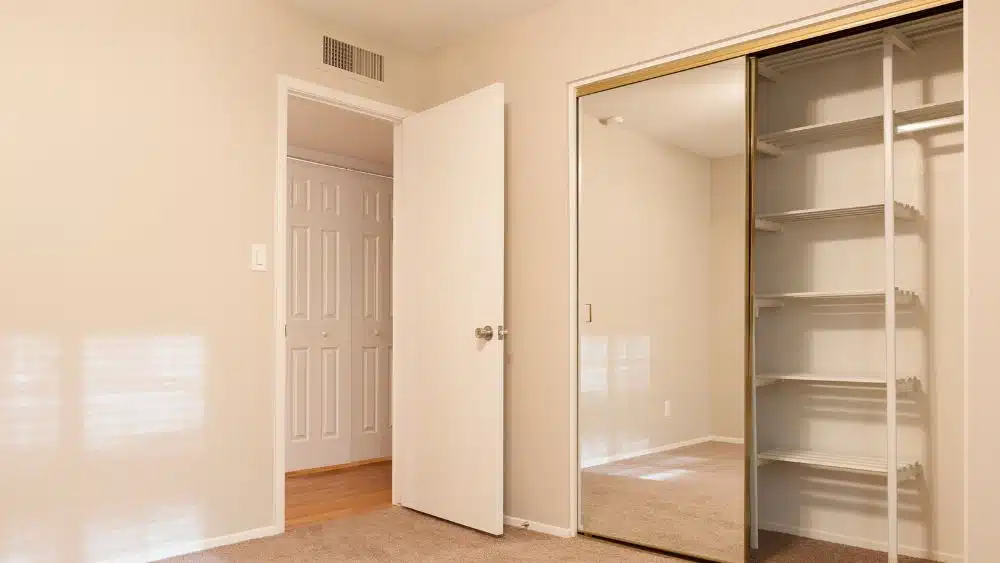 Room with a standard closet with sliding mirror doors.