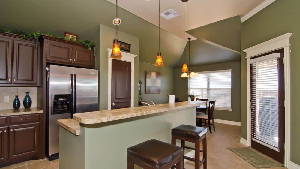 Large, classic kitchen with dark brown cabinets and sage green walls.