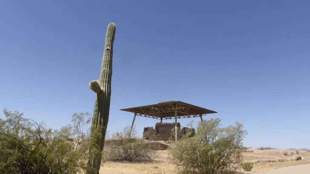 View of Casa Grande Ruins, an ancient native structure, with a tall saguaro on the left