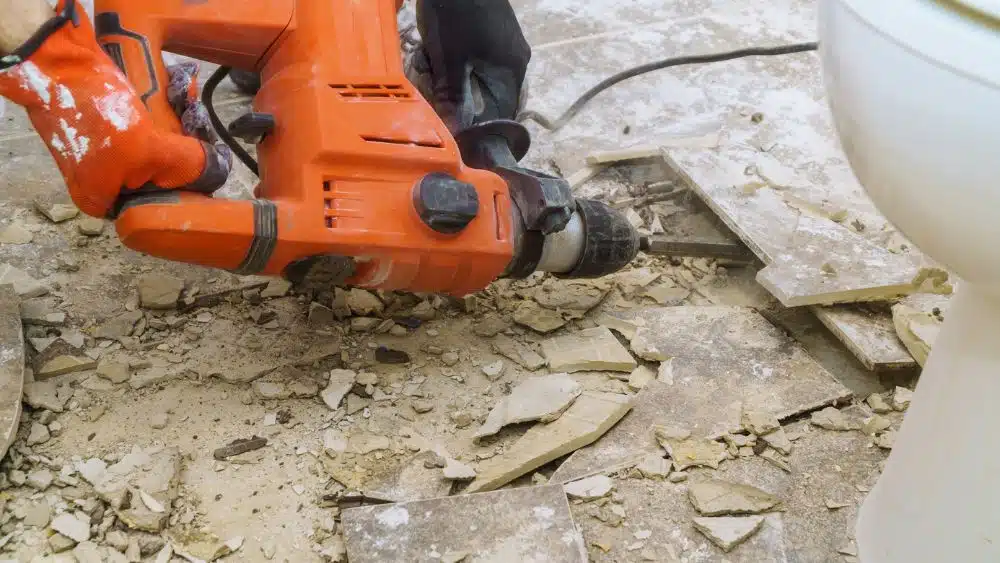 Power tool prying up tile.