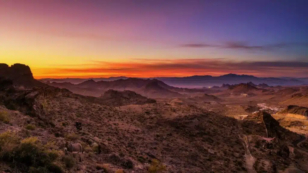 View of Black Mountain range in western Arizona at sunset with colors ranging from (left) yellows, oranges and reds to (right) pinks, blues and purples
