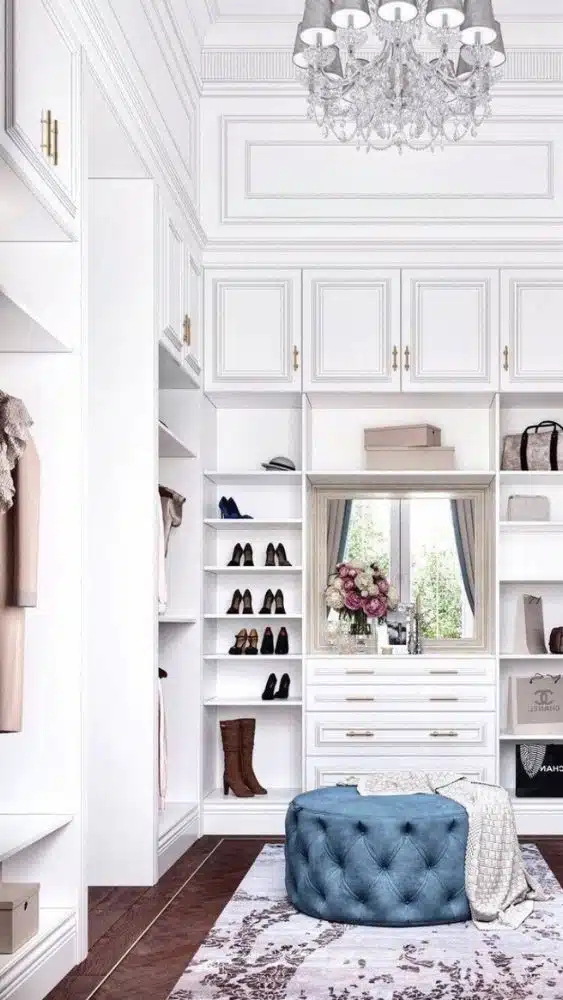 Large closet with a blue ottoman on the floor. A window lets in natural light on one side.