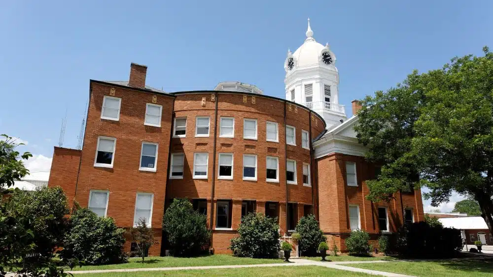 A three story brick building with a white domed clocktower.
