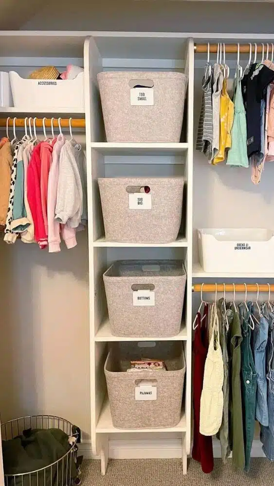 Closet with children's clothes hanging and vertical shelves with cloth baskets.