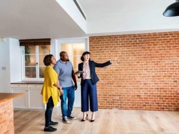 Realtor showing couple a modern industrial home interior