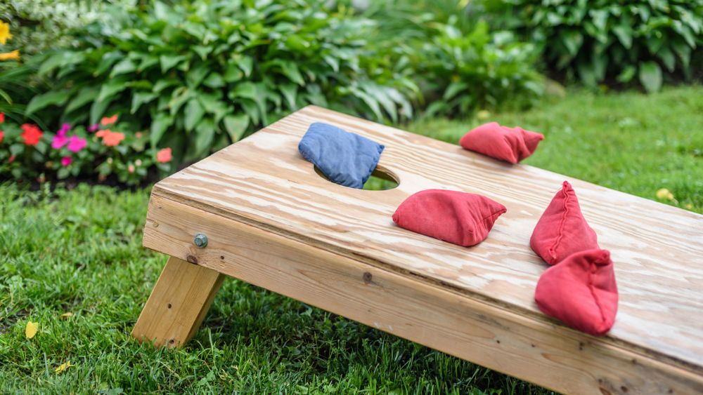 Cornhole game set up in a grassy backyard.