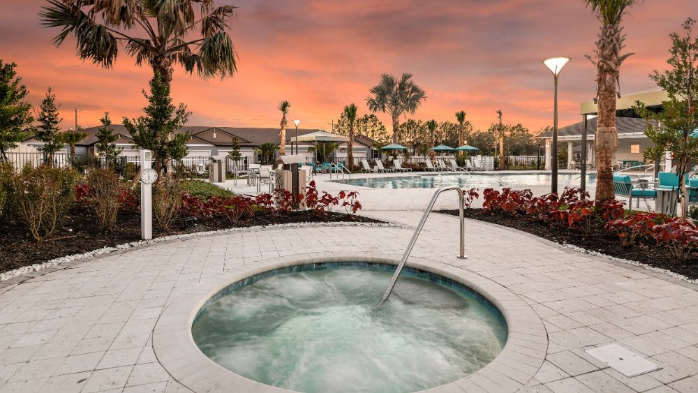 A community hot tub, with a pool and clubhouse in the background.