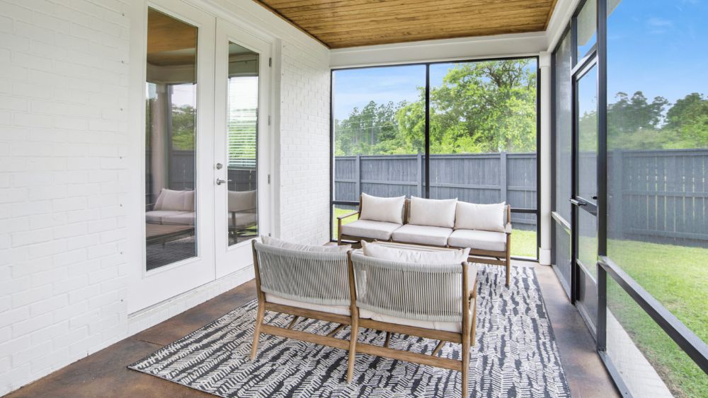 Sunroom looking out onto a grassy backyard on a sunny day.